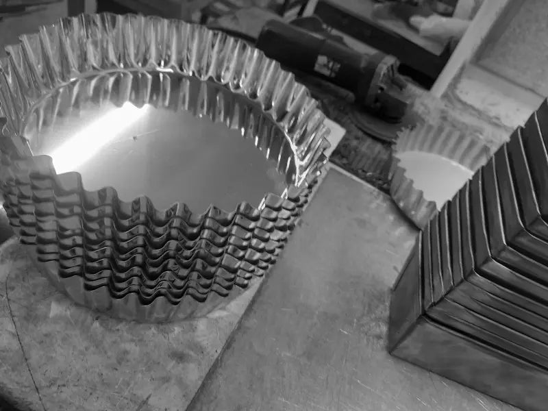 Stivă de inele profesionale pentru tartă și quiche cu margini canelate, fabricate din inox AISI 304. Detaliu din atelierul de producție, ideale pentru laboratoare de cofetărie și patiser